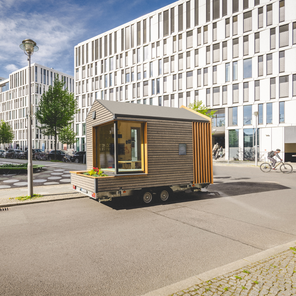 TINY SPACE – mobiler Premium-Arbeitsraum auf Rädern vor urbanem Hintergrund